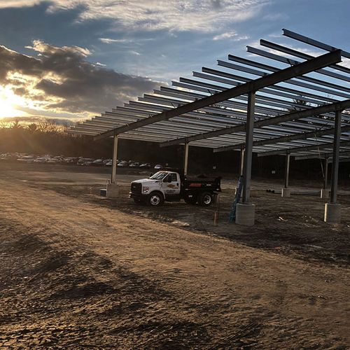 Truck parked under completed solar carport structure at sunset